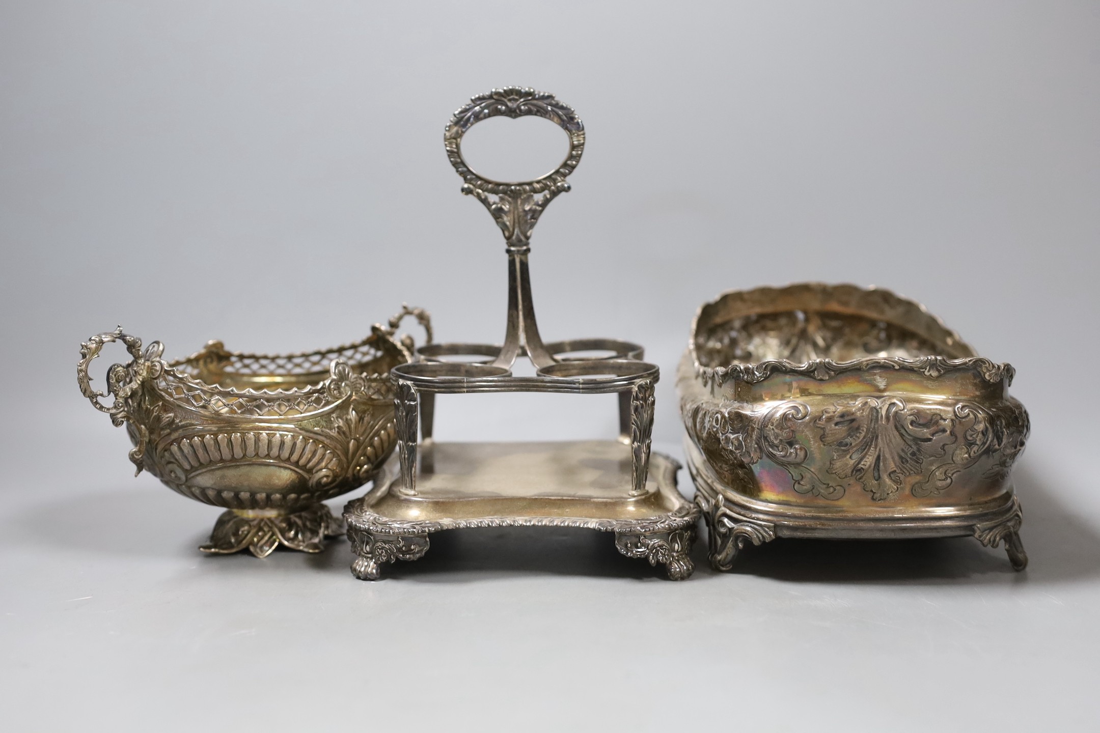 A George III silver cruet stand, no bottles, London, 1816, a late Victorian embossed oval silver basket, London, 1890 and an embossed oval silver cruet stand, no handle or bottles.
